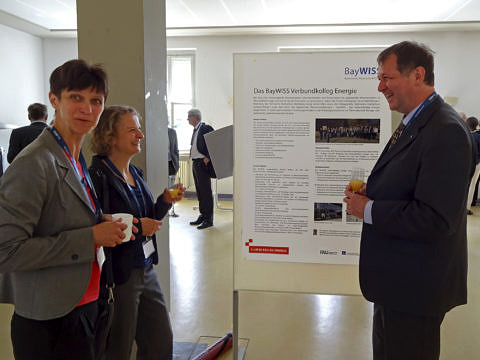 Dr. Wismet, Dr. Seffer und Dr. Fuchs unterhalten sich beim Empfang vor den Poster des Verbundkolleg Energie